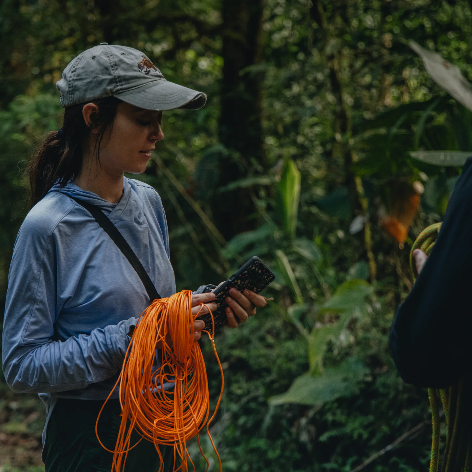 A researcher in the rainforest holding a coil of orange cable