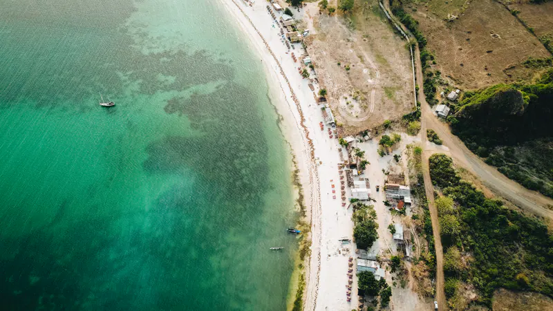A white beach curving along green shallows, seen from above