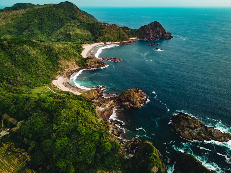 Green hills dropping into a dark blue sea along a rocky coast