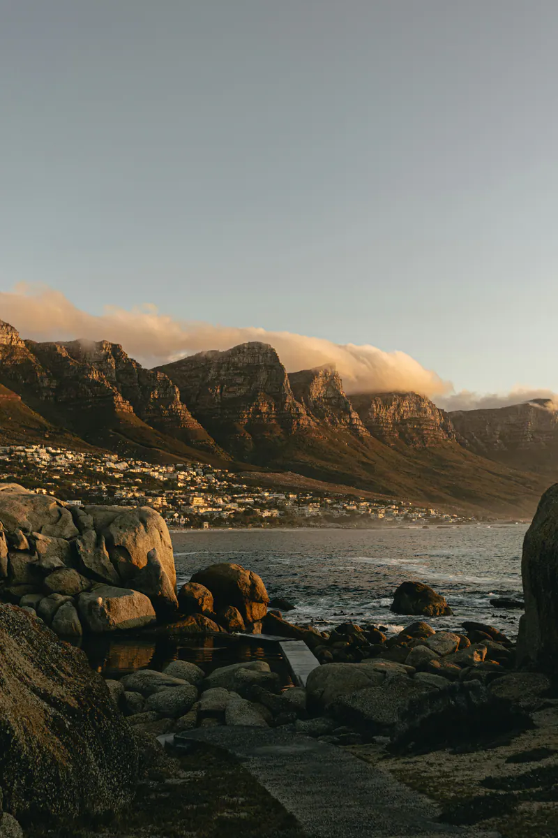 Boulders on the shore at sunset, cloud spilling over the mountain ridge