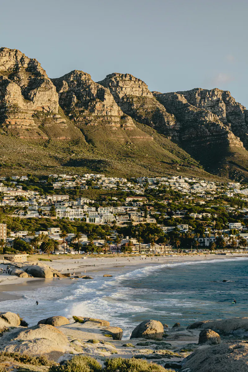 A bay with a white beach and a town below a wall of mountains