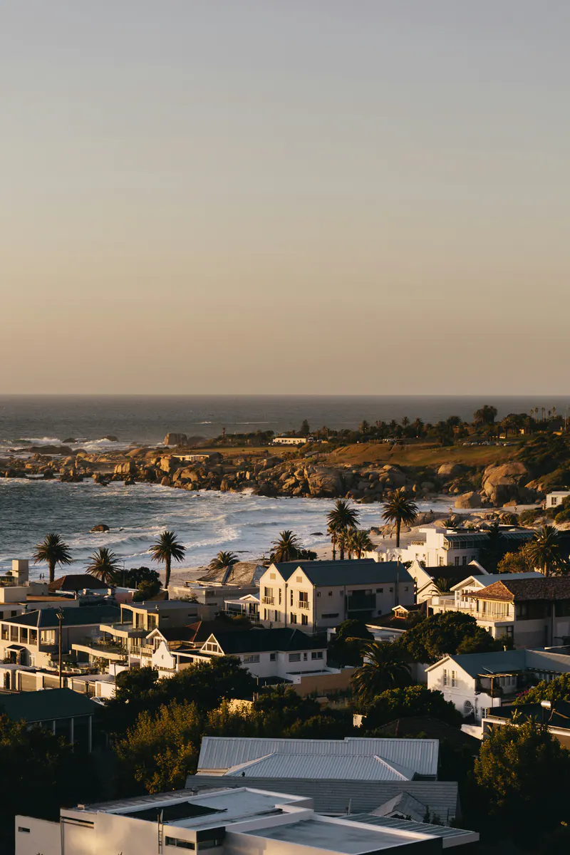 Rooftops and palms above a rocky coast at sunset