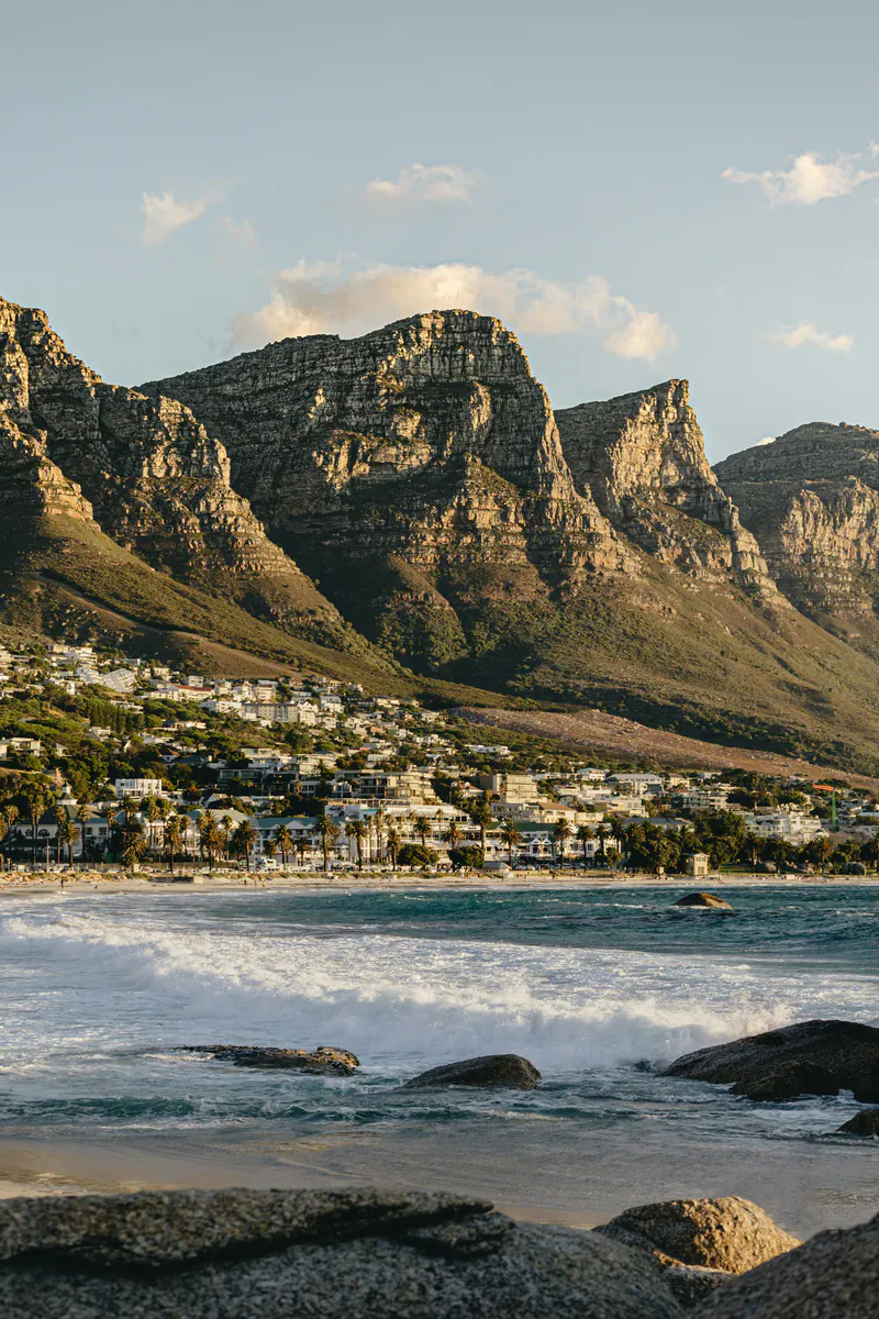Surf rolling into a bay below steep mountains