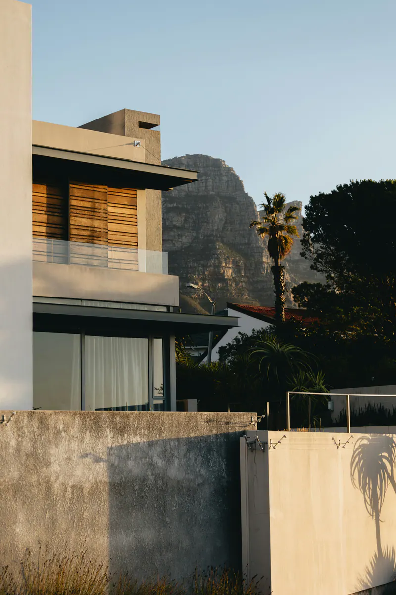 A modern concrete house in evening light, with a mountain behind