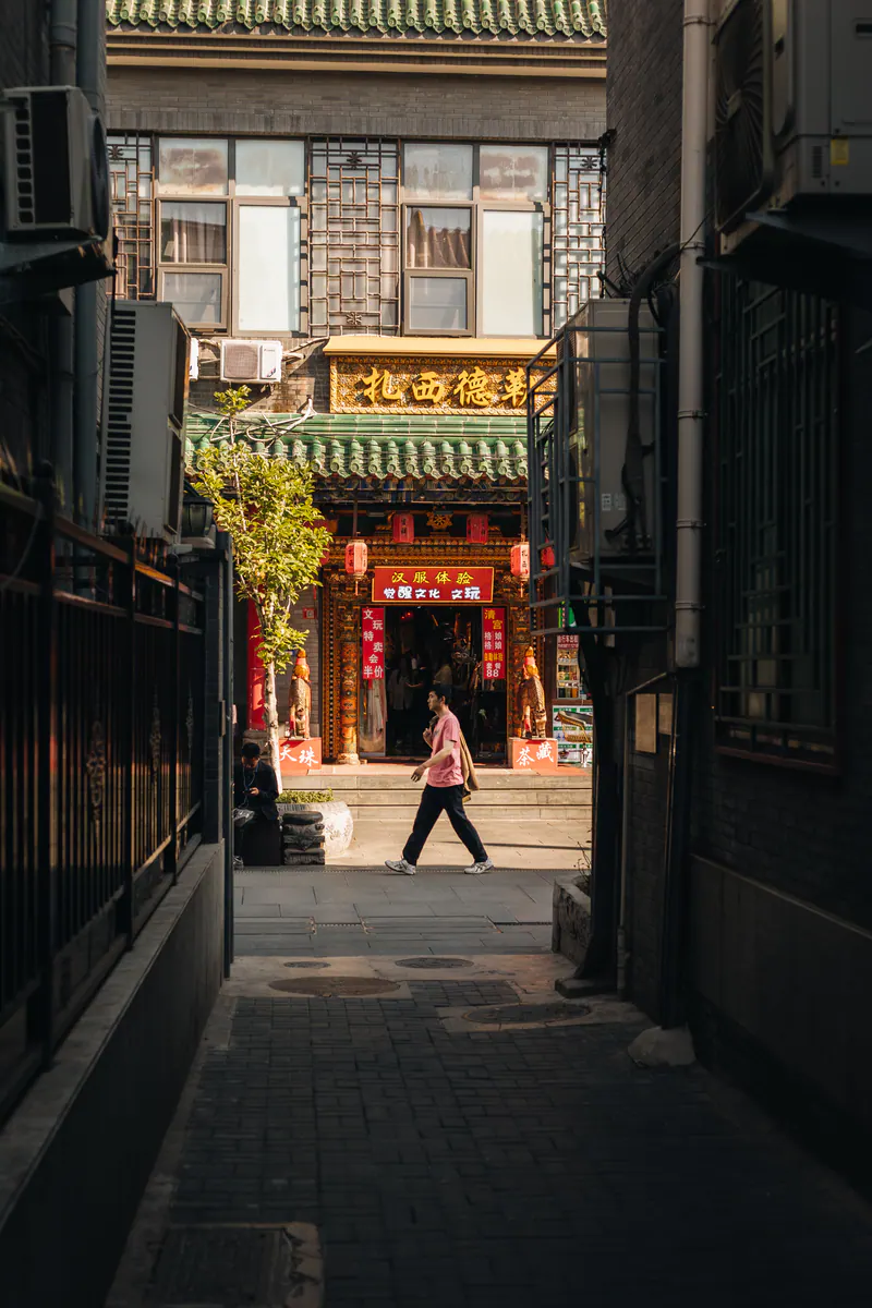 Someone walking past a temple gate at the end of a dark alley
