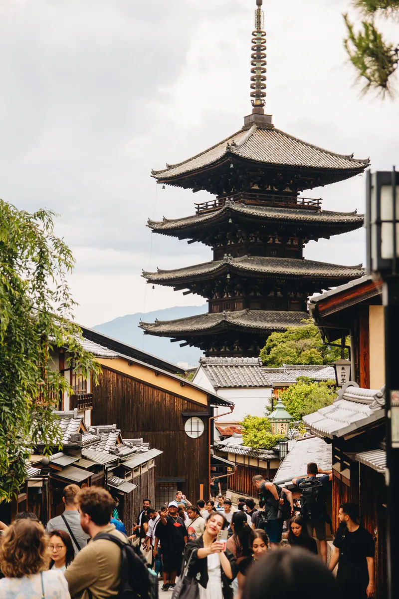 A five-storey pagoda above a street crowded with visitors in Kyoto