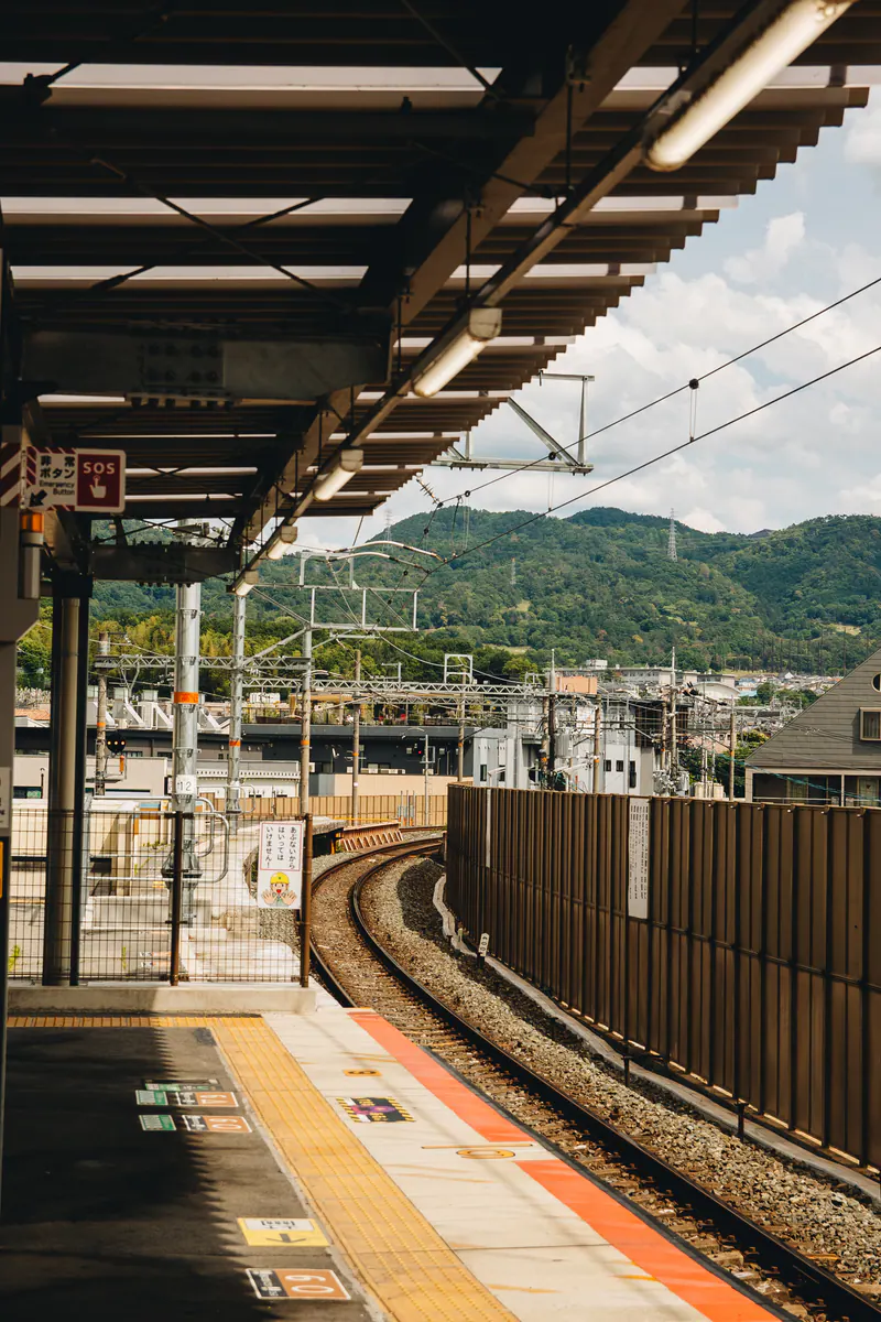 A railway track curving away from a station platform towards green hills