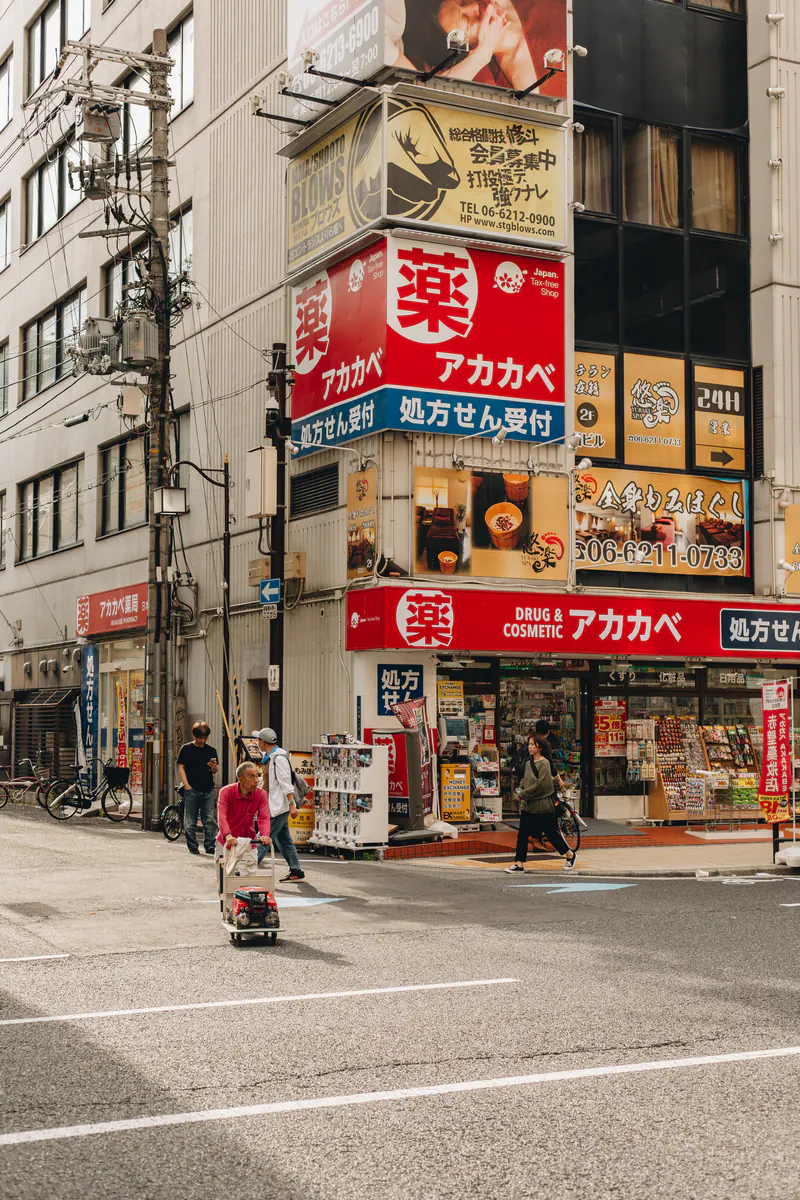 A corner pharmacy in Osaka covered in red signs