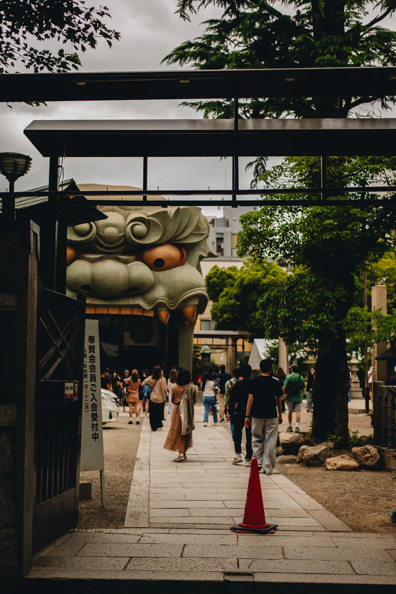 Visitors walking towards a giant stone lion head at a shrine in Osaka