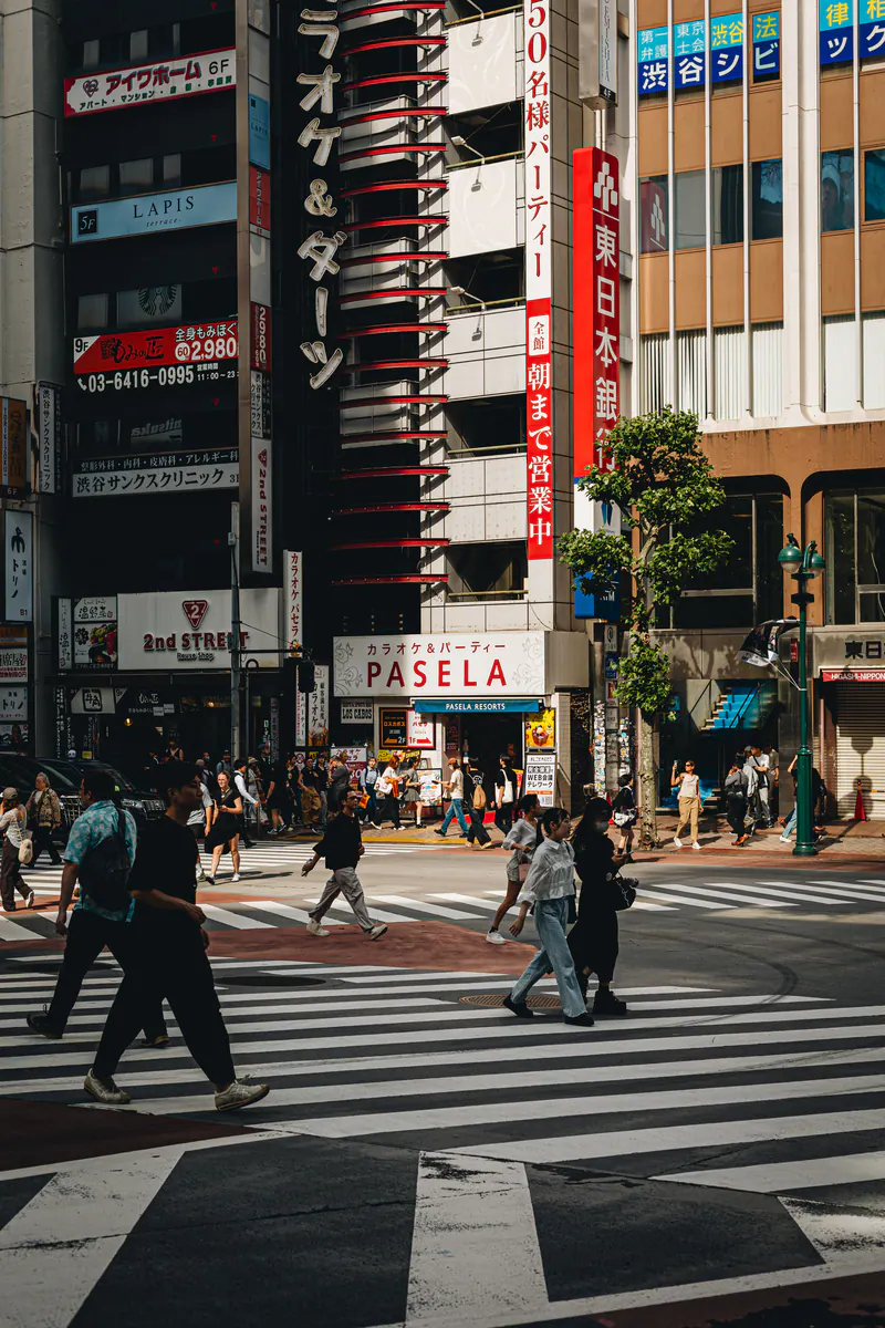 People on a crossing in Tokyo, under tall buildings covered in signs
