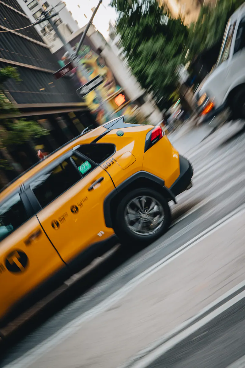 A yellow taxi blurring past on a tilted street