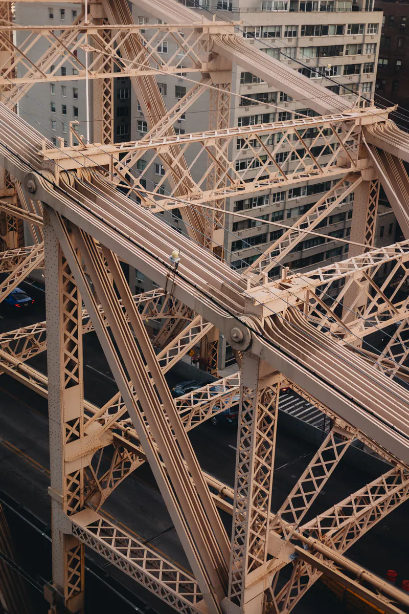 The pale pink steelwork of a bridge against apartment blocks