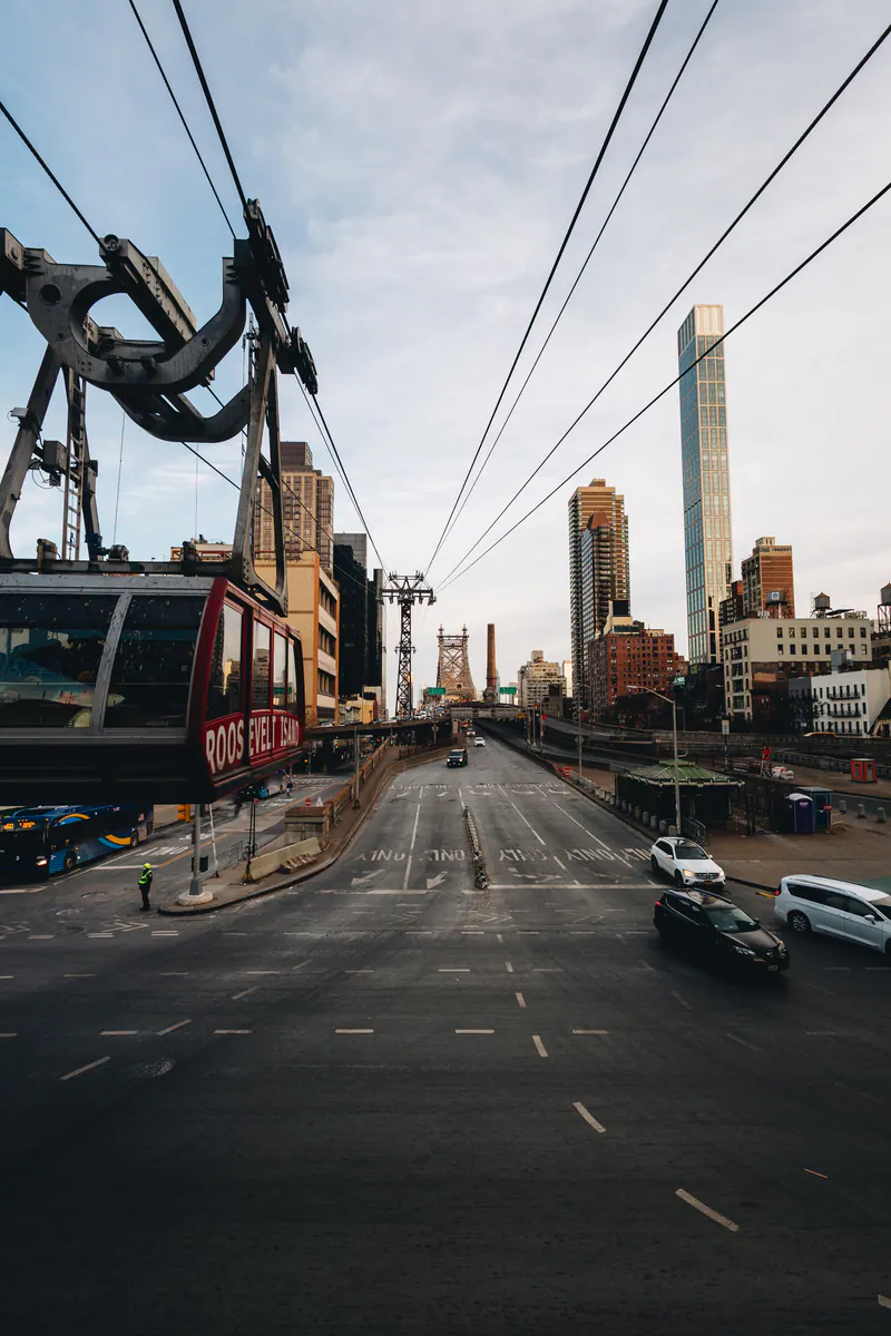 A red cable car gliding over an avenue towards the skyline