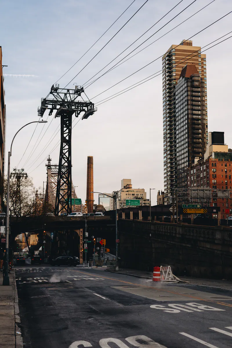 A cable car tower over a bus lane, with a brick tower block behind