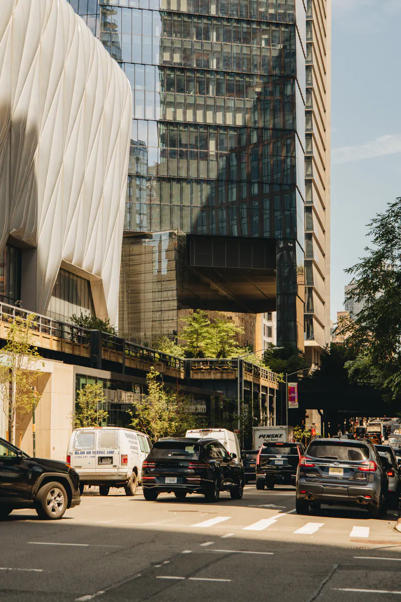 Cars waiting at a crossing below glass and steel towers