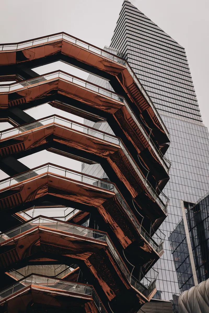 The copper staircases of the Vessel against a glass tower