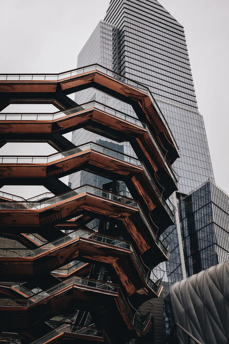 The stacked staircases of the Vessel from below, with a glass tower behind