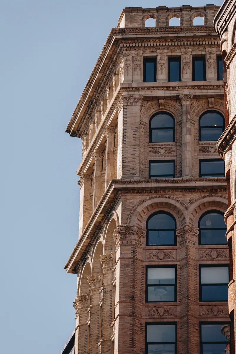 The top floors of a brick building with arched windows against a blue sky