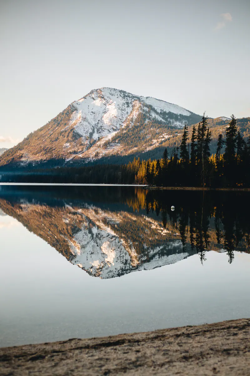 A snow-capped mountain mirrored in a still lake