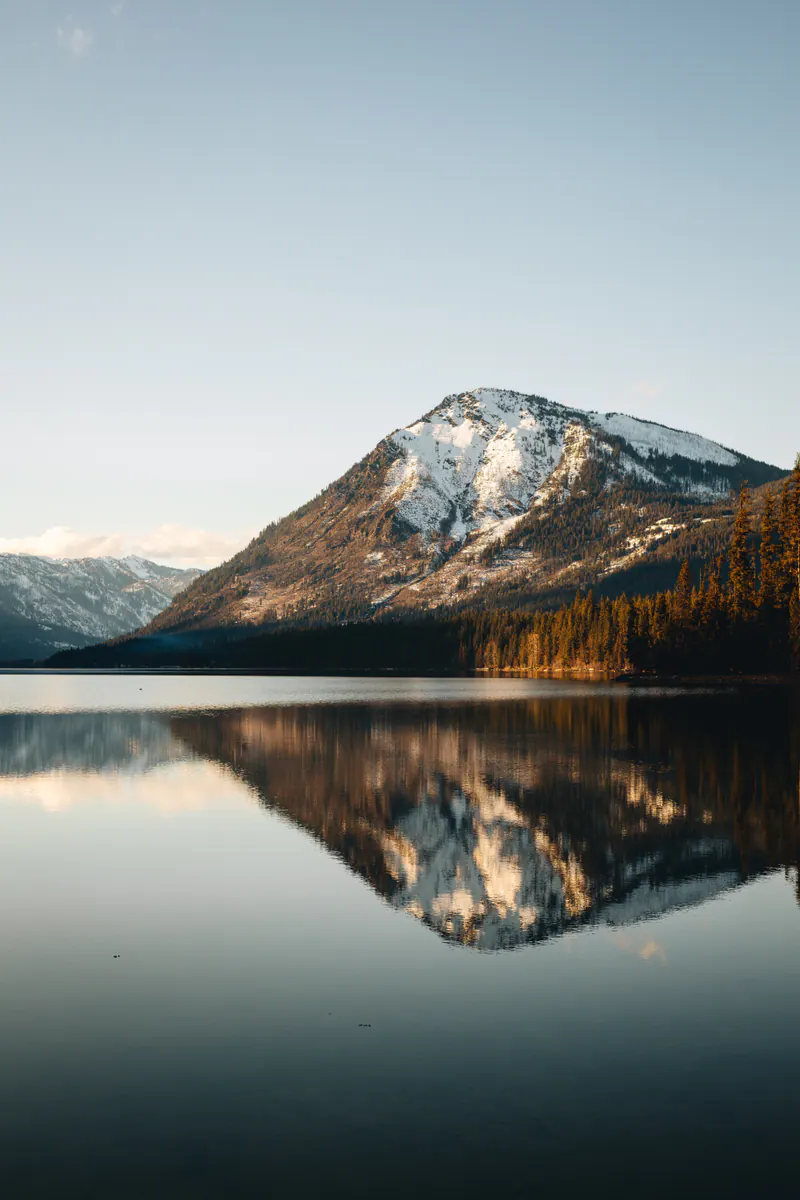 A mountain reflected in a dark, calm lake under a clear sky